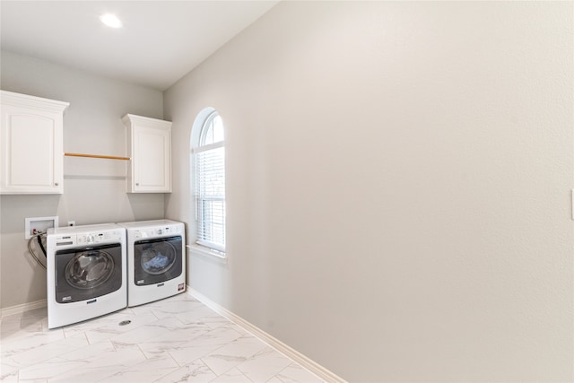 clothes washing area featuring cabinets and washer and clothes dryer