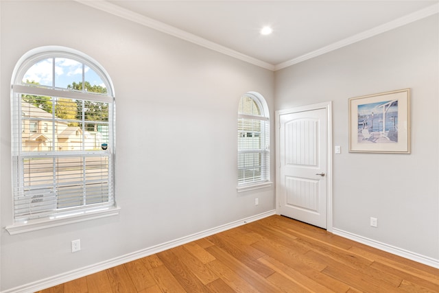 empty room with crown molding, plenty of natural light, and light hardwood / wood-style floors