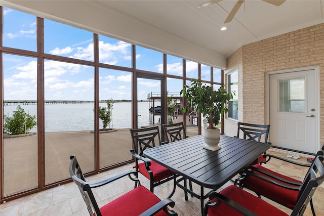 sunroom featuring ceiling fan and a water view