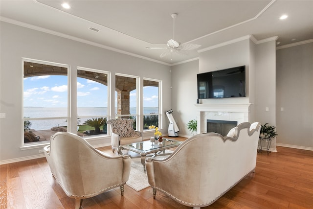 living room with a premium fireplace, ceiling fan, ornamental molding, and wood-type flooring