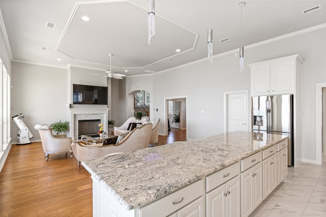 kitchen with pendant lighting, a premium fireplace, ceiling fan, light wood-type flooring, and white cabinets