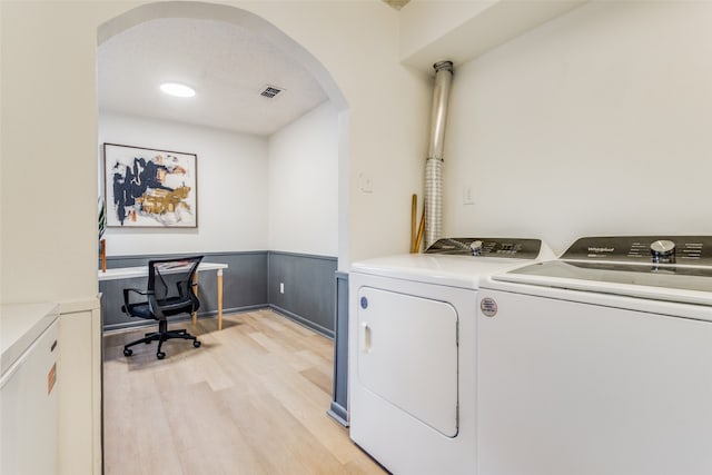 laundry area featuring light wood-type flooring, a textured ceiling, and washer and clothes dryer