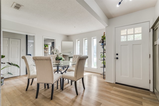 dining room featuring a textured ceiling and light hardwood / wood-style floors