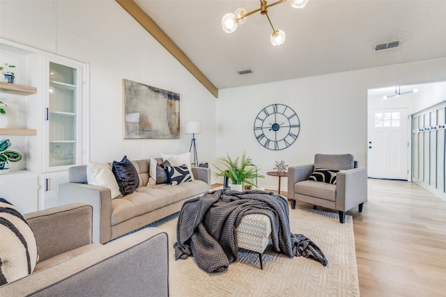 living room featuring lofted ceiling with beams, a notable chandelier, and light hardwood / wood-style floors