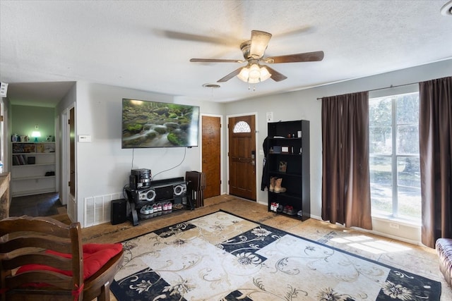 living room with ceiling fan, a textured ceiling, and a healthy amount of sunlight