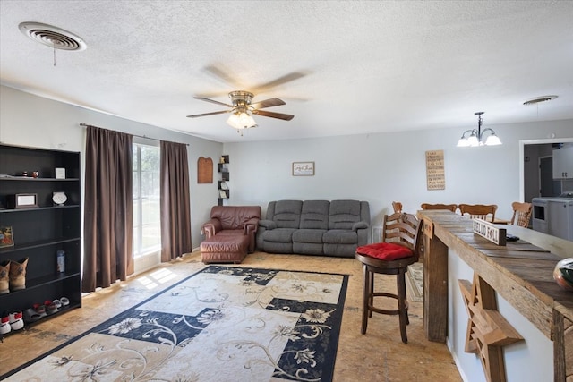 living room with ceiling fan with notable chandelier and a textured ceiling