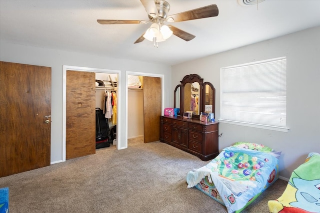 carpeted bedroom featuring multiple closets and ceiling fan