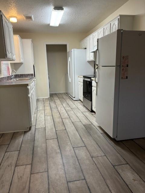2413 Markland St, Irving, TX 75060 - kitchen with freestanding refrigerator, electric stove, a sink, wood finish floors, and a textured ceiling