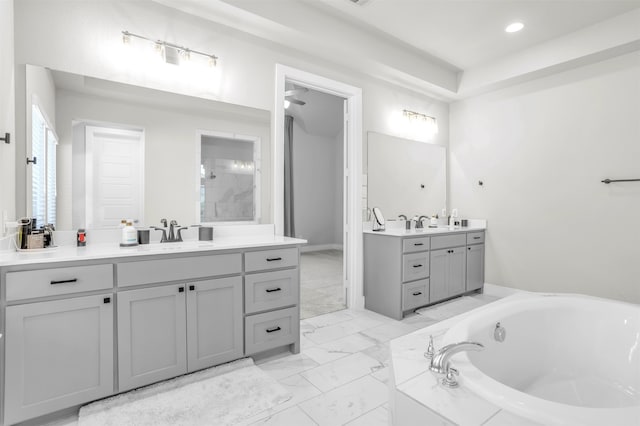 bathroom featuring a relaxing tiled tub and vanity