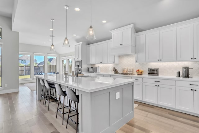 kitchen with pendant lighting, a center island with sink, a breakfast bar area, white cabinetry, and sink