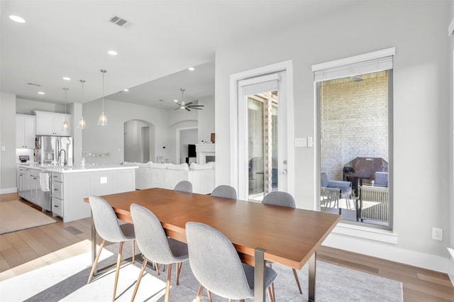 dining area with ceiling fan, light hardwood / wood-style floors, and sink