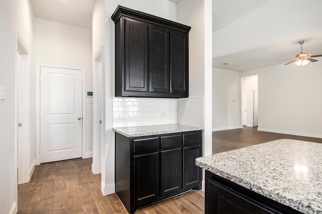 kitchen with backsplash, hardwood / wood-style flooring, light stone counters, and ceiling fan