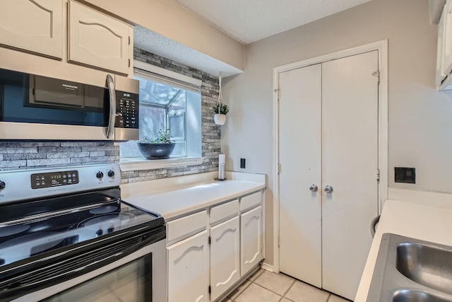 kitchen featuring appliances with stainless steel finishes, light tile patterned flooring, and white cabinets