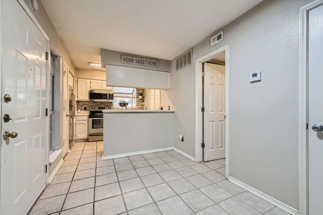 kitchen featuring white cabinetry, stainless steel appliances, light tile patterned flooring, and kitchen peninsula