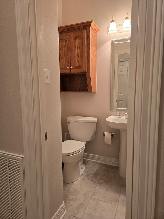 bathroom with toilet, sink, and tile patterned floors