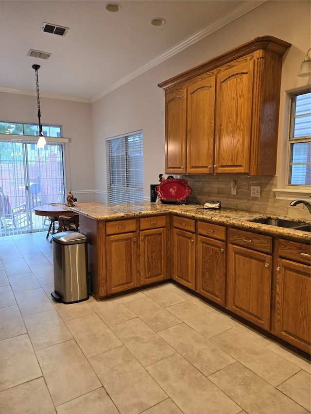 kitchen with light tile patterned floors, crown molding, kitchen peninsula, hanging light fixtures, and decorative backsplash