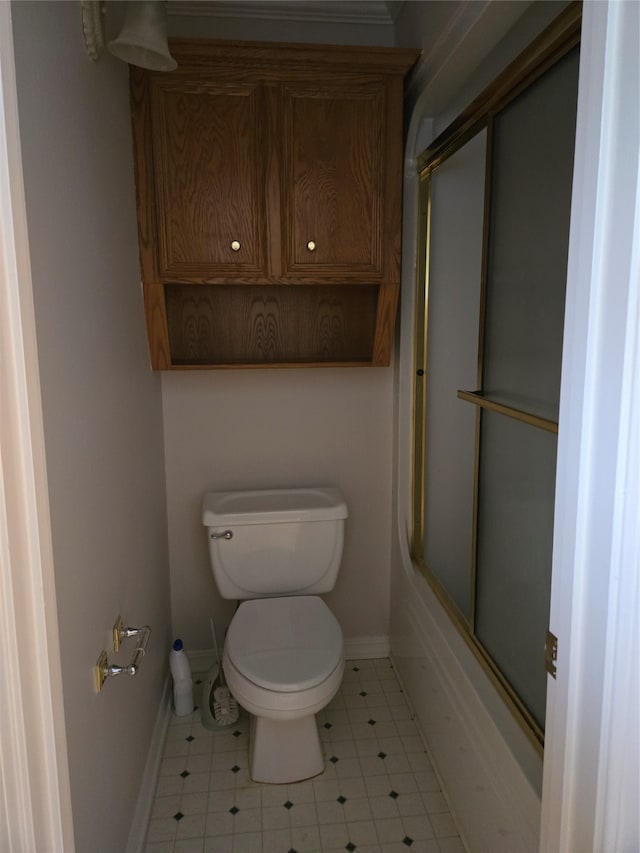 bathroom featuring toilet and bath / shower combo with glass door