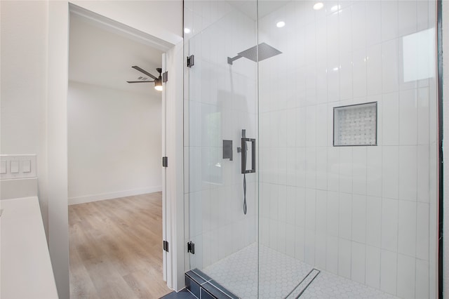 bathroom with ceiling fan, wood-type flooring, and a shower with shower door