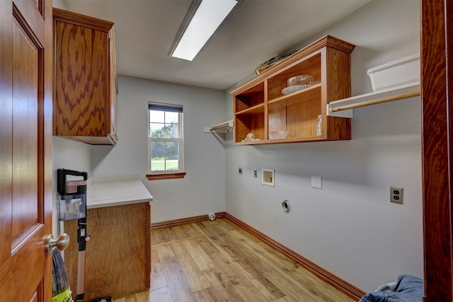 clothes washing area featuring gas dryer hookup, light wood-type flooring, hookup for an electric dryer, washer hookup, and cabinets