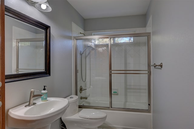 full bathroom with toilet, sink, and combined bath / shower with glass door