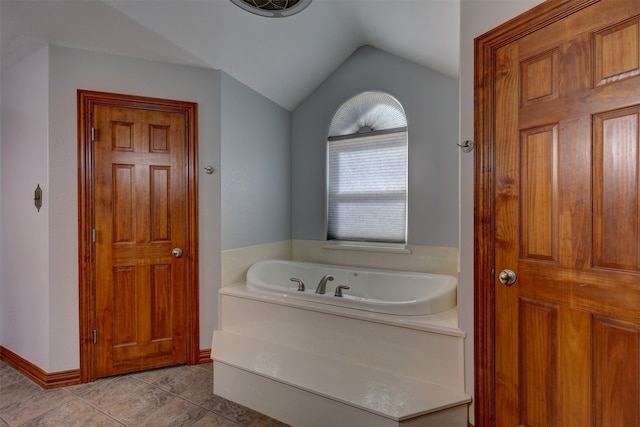 bathroom featuring tile patterned flooring, a bathing tub, and vaulted ceiling