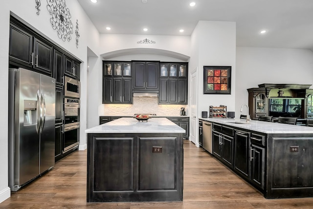 kitchen featuring light stone counters, stainless steel appliances, sink, and an island with sink