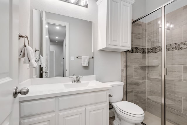 bathroom with vanity, a shower with shower door, and toilet