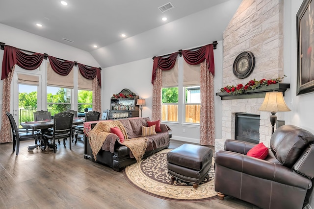 living room featuring wood-type flooring, vaulted ceiling, a wealth of natural light, and a fireplace