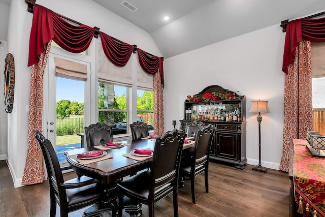 dining room with bar area, dark hardwood / wood-style floors, and vaulted ceiling