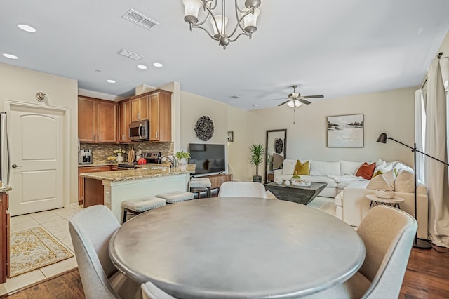 dining room featuring light wood-type flooring and ceiling fan with notable chandelier