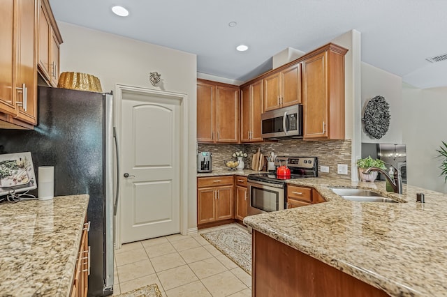 kitchen with light stone countertops, light tile patterned floors, backsplash, stainless steel appliances, and sink