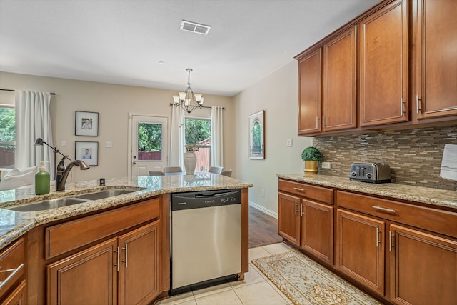 kitchen featuring a notable chandelier, light stone countertops, stainless steel dishwasher, and sink