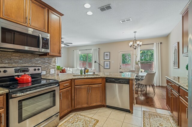 kitchen featuring ceiling fan with notable chandelier, pendant lighting, appliances with stainless steel finishes, light hardwood / wood-style floors, and sink