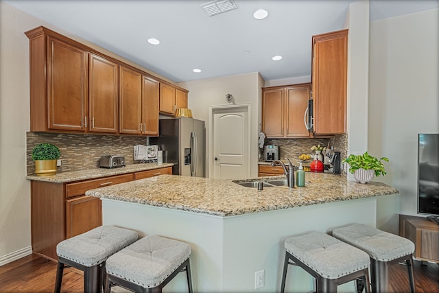 kitchen featuring light stone countertops, appliances with stainless steel finishes, sink, dark hardwood / wood-style floors, and kitchen peninsula