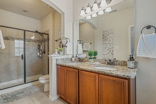 bathroom with vanity, toilet, tile patterned flooring, and a shower with door