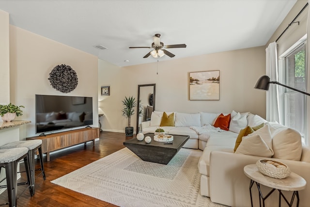 living room featuring dark wood-type flooring and ceiling fan