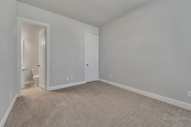 unfurnished bedroom featuring ensuite bathroom and light colored carpet