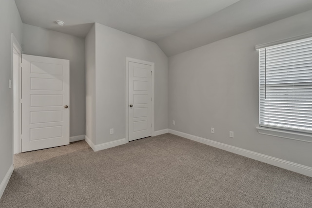 unfurnished bedroom with vaulted ceiling, light colored carpet, and a closet