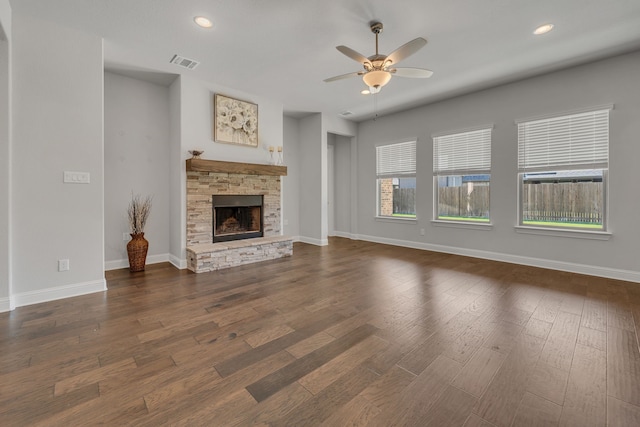 unfurnished living room featuring ceiling fan, dark hardwood / wood-style floors, and a stone fireplace