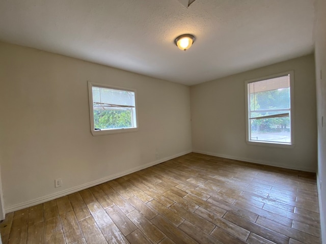 unfurnished room with light wood-type flooring and a textured ceiling