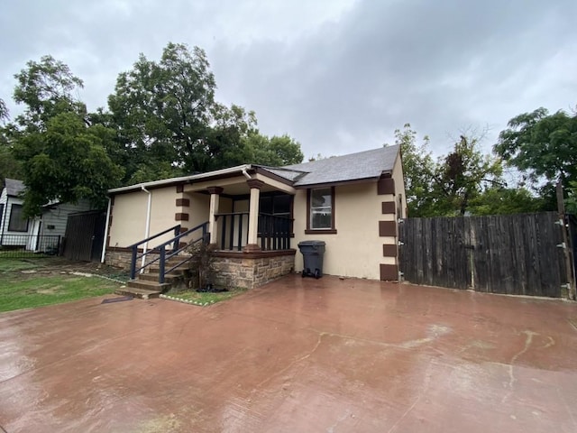 view of front of home with stucco siding, roof with shingles, and fence