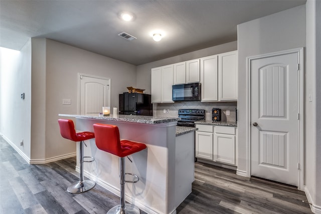 kitchen with black appliances, white cabinetry, a kitchen island, and dark wood-type flooring