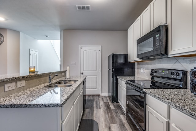 kitchen with black appliances, sink, dark hardwood / wood-style floors, stone countertops, and white cabinets