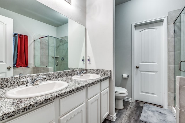 bathroom featuring a shower with door, vanity, toilet, and hardwood / wood-style flooring