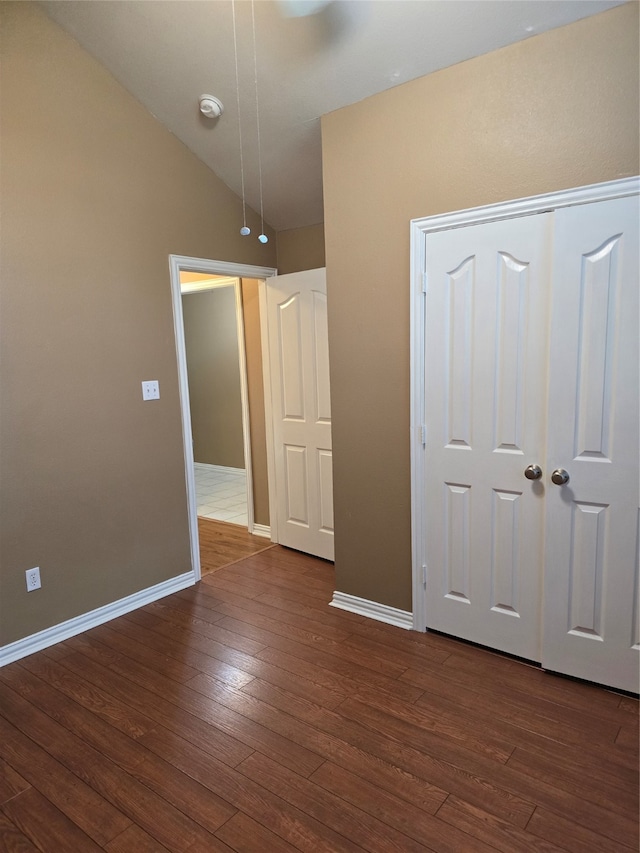 unfurnished bedroom featuring a closet, lofted ceiling, and dark hardwood / wood-style floors