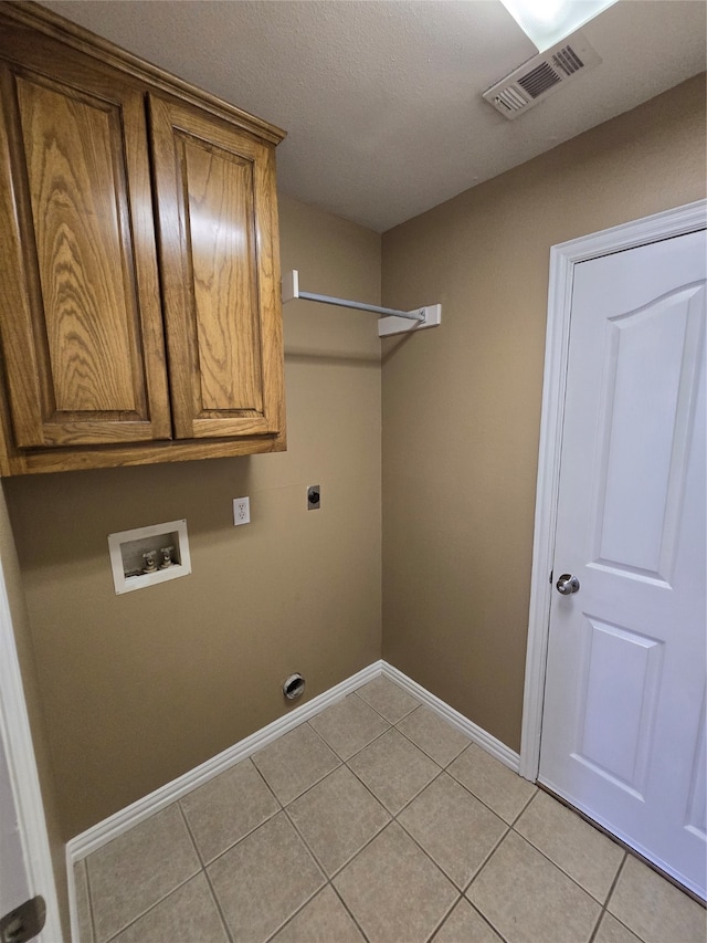 washroom with hookup for a washing machine, electric dryer hookup, light tile patterned flooring, cabinets, and a textured ceiling