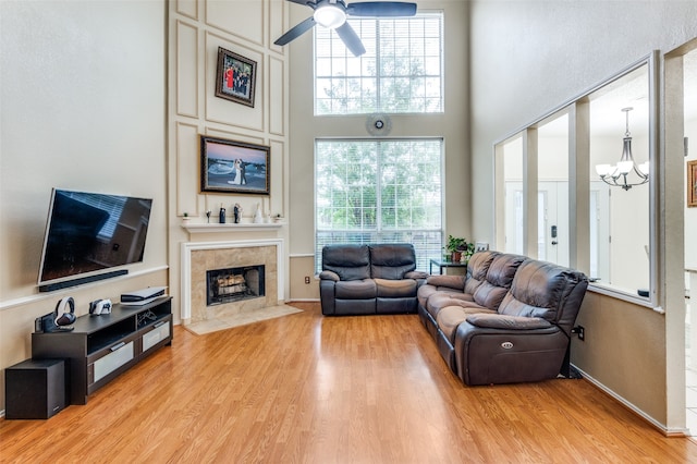 living room with ceiling fan with notable chandelier, plenty of natural light, and light hardwood / wood-style floors