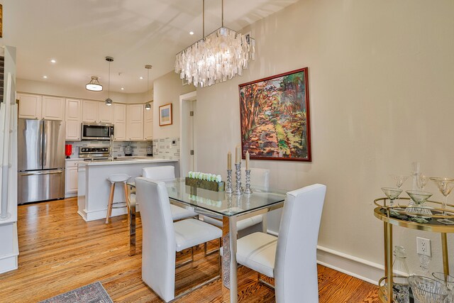 dining space with light wood-type flooring and a notable chandelier