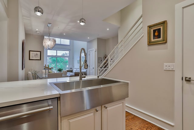 kitchen featuring pendant lighting, a notable chandelier, sink, hardwood / wood-style flooring, and stainless steel dishwasher