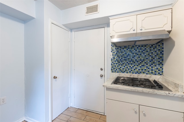 kitchen with white cabinets, stainless steel gas stovetop, decorative backsplash, and light hardwood / wood-style flooring